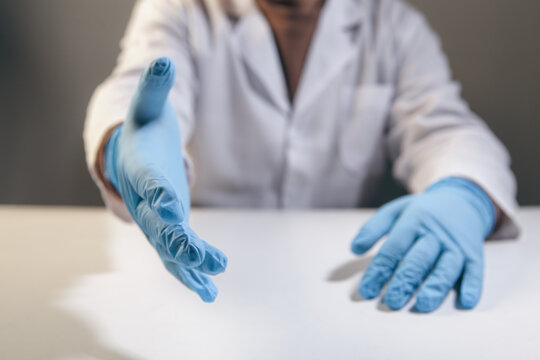Close up of medical doctor hands in blue latex gloves on table.