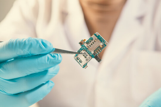 Technician fixing circuit board with tweezers, closeup view