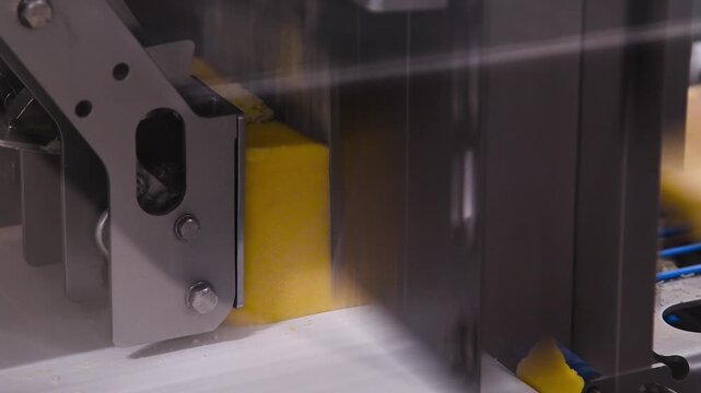 Conveyor belt with pieces of yellow cheese moving on it.