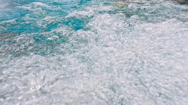 Close-up view of bright blue bubbling water filled with bubbles.