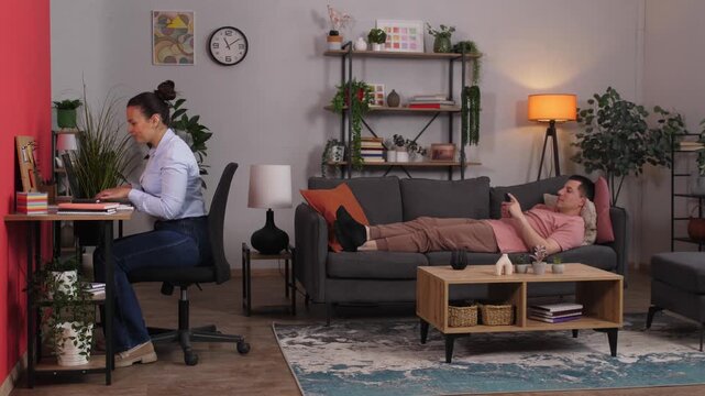 Frustrated woman interrupting lazy husband watching tv