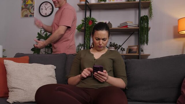 Woman ignoring her stressed partner while using her smartphone