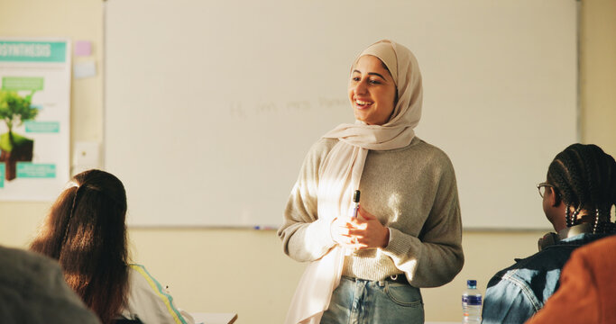 Education, muslim woman and teacher in classroom at high school with study tips, learning or smile. Curriculum, person and female educator with students for teaching or academic support in lesson