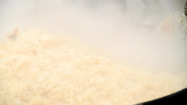 Tasty pilaf in a cauldron on fire in the open air at street food festival