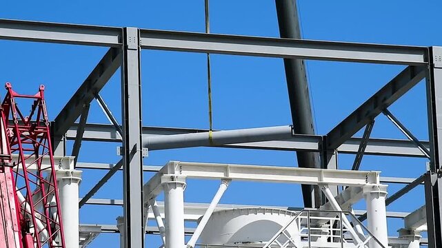 A construction crane with a long boom is used for lifting and installing metal structures.