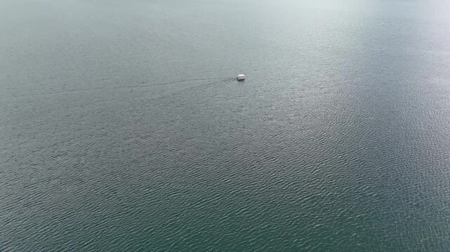 4K Drone Aerial View of Calm Mountain Lake With Small Floating Boat and Water Texture.