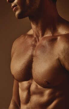Close up of fit man muscular chest and abdominal muscles with athletic physique bodybuilder strength definition physical exercise training masculine sculpted wellness lifestyle lighting