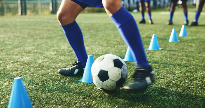 Legs, soccer and person with cone for exercise, game practice or running drills for training. Football player, feet and man with equipment on field for agile fitness, sports challenge or ball control