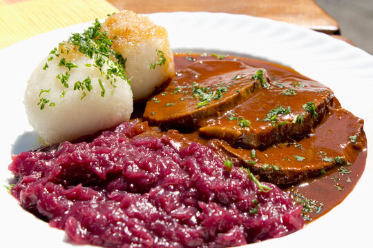 Plate of sauerbraten marinated beef with red cabbage and potato dumpling