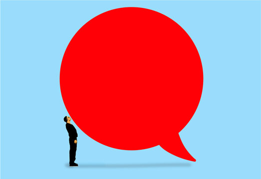 Businessman looking up at a large red speech bubble symbolizing communication and opinion