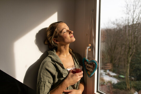 Young woman at the window enjoying the sunshine