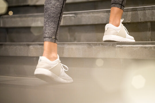 Close up of female legs with white sport sneakers running up the stairs