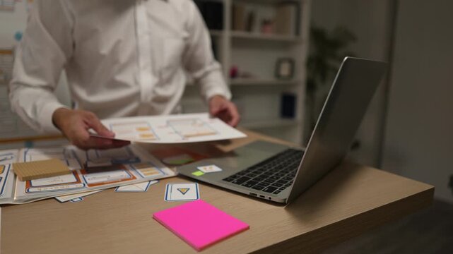 Business professional reviewing mobile application wireframes and user interface layouts while planning digital product development, UX design strategy, software features, and workflow optimization.
