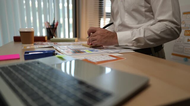 Business professional reviewing mobile application wireframes and user interface layouts while planning digital product development, UX design strategy, software features, and workflow optimization.