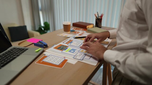 Business professional reviewing mobile application wireframes and user interface layouts while planning digital product development, UX design strategy, software features, and workflow optimization.