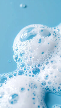 White foamy soap bubbles spread on smooth blue surface, clean hygiene and skincare concept, airy composition. Close-up.