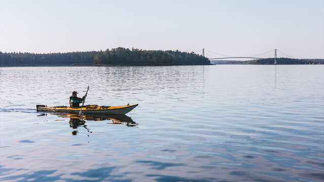 Person sea kayaking near a large suspension bridge, Maine.