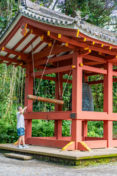 A tourist striking the Bon-Sho bronze bell at the Byodo-In Temple