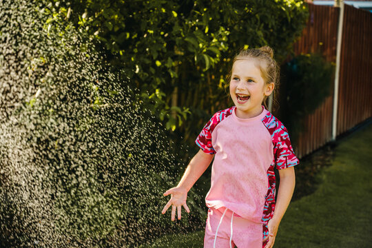 Happy child playing in backyard sprinkler on sunny summer day