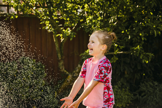 Happy child playing in backyard sprinkler on sunny summer day