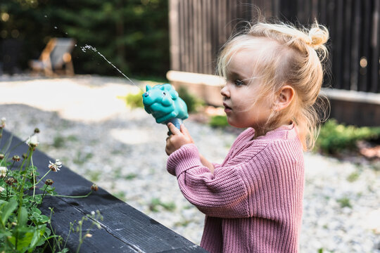 Little blonde girl shooting a dinosaur water gun