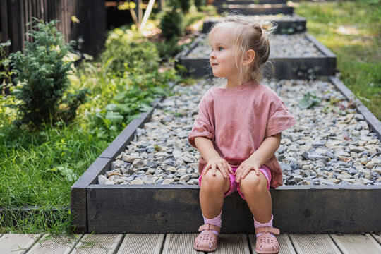 Little blonde girl sitting on garden steps
