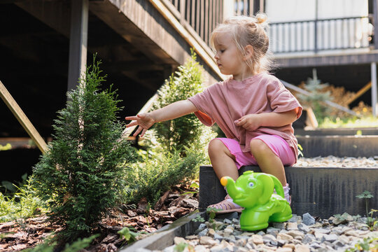 Curious toddler girl reaching for a small plant