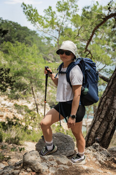 Woman with trekking pole hiking on a forest trail