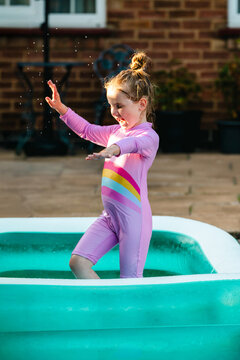 Playful child dancing in inflatable backyard pool