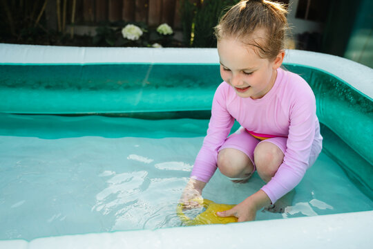Young child playing in inflatable backyard pool, summer holiday