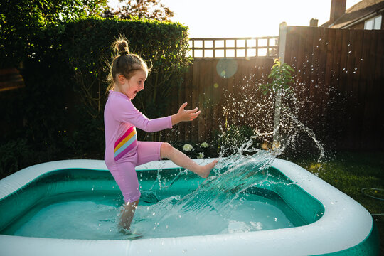 Joyful child splashing in inflatable backyard pool, summer holidays