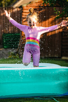 Excited child splashing in inflatable backyard pool