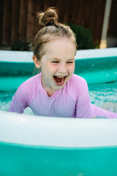 Young child playing in inflatable backyard pool, summer holiday