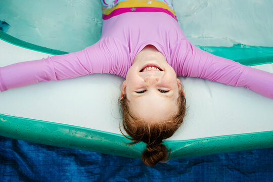Happy child relaxing in inflatable pool, top view