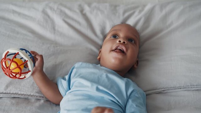 Charming smiling infant lying in waterbed, carefree childhood, portrait shot. Happy family moments, parenting and healthcare for children, healthy african american child, toothless smile on cute face