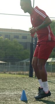 Man, running and soccer player with cone for training, exercise or practice for competition outdoor. Athlete, person or footballer on field with cardio workout, sports drill or equipment for fitness.