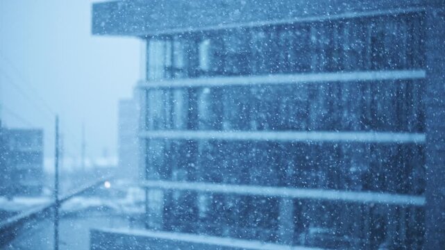Moody shot of snow falling in front of a modern building