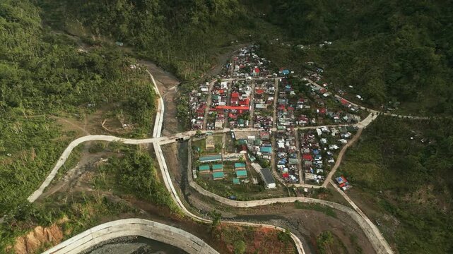 Aerial dolly over Barangay Obi in Caramoran, Catanduanes, showing a rural village surrounded by homes, roads, and lush tropical hills