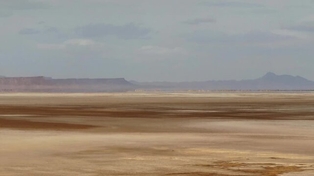 Scenic aerial drone view of the vast Chott el Djerid salt lake flat landscape with distant mountains under a cloudy sky in Tunisia. Ideal for travel and geological themes