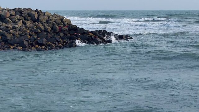 Ocean waves washing over rocky breakwater at Gomti Ghat, Dwarka. Perfect for Hindu pilgrimage docs, sacred river meets sea, Gujarat coastal tourism and spiritual journey content.