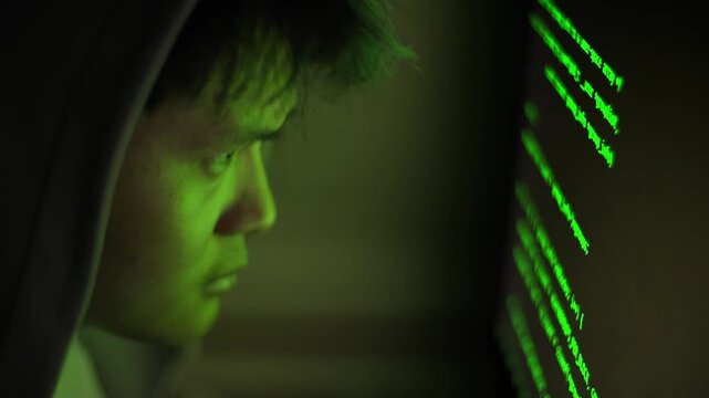 Close-up profile of a focused Asian programmer in a dark room breaching security databases or configuring global VPN routing networks