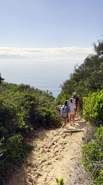 Vertical. Mom with twin girls hiking along coastal trail of scenic Robberg nature reserve and marine protected area