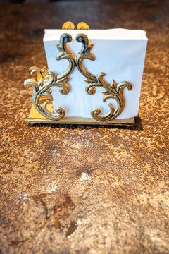 A beautifully crafted white box with intricate gold swirl designs sits on a textured brown surface, showcasing its elegant details and unique style.