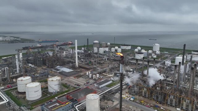 Aerial view of a chemical plant at sunset. Drone shot. Curling fire and cumin smoke filling the sky. Smoking chimneys from the factory. Chimneys of an oil refinery at sunrise pollute the environment