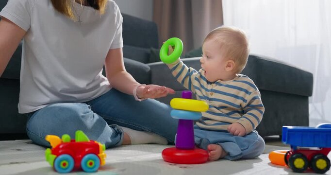 A toddler engaged in developmental playtime with a parent at home, exploring colorful stacking rings and toy vehicles, fostering early learning and motor skills in a cozy living room