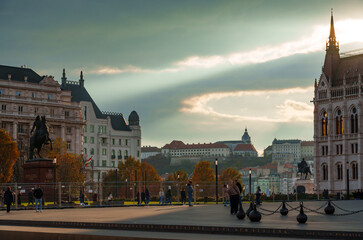 Obraz premium Panoramic View of Budapest Cityscape with Historical Architecture and Equestrian Statue under Dramatic Sunset Sky in Hungary Europe Urban Landscape at Golden Hour