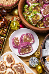 Fototapeta premium Variety of Turkish delight rolls with pistachios and coconut on plates with festive Christmas ornaments on a wooden table