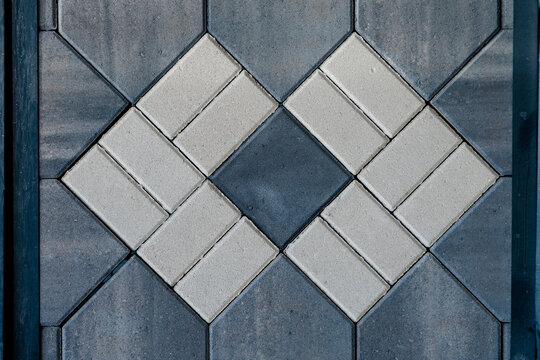 Interlocking grey and white pavers creating geometric diamond pattern