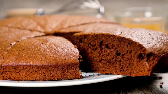 Slices of homemade chocolate cake served on white plate with baking utensils in background