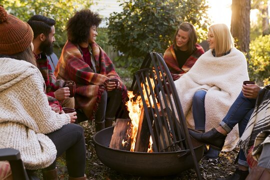 Friends enjoying cozy bonfire gathering outdoors at sunset